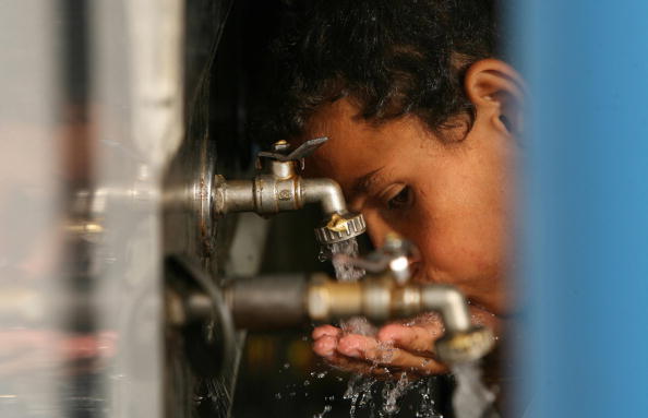 A Palestinian boy drinks water from a fa