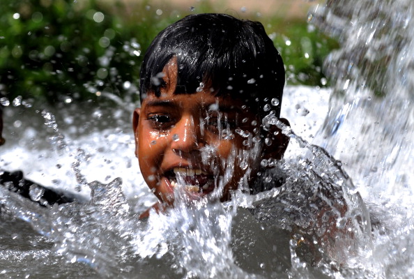 A child cools himself under a tube well