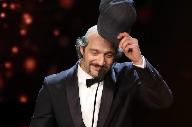 Claudio Santamaria nel momento in cui si toglie il cappello, svelando la vistosa pelata
