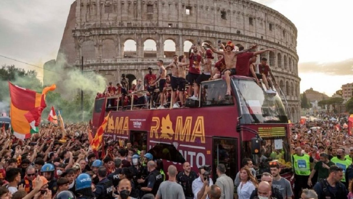 Il bus della Roma davanti al Colosseo e circondato dalla folla di tifosi in festa per la conquista della Conference League.