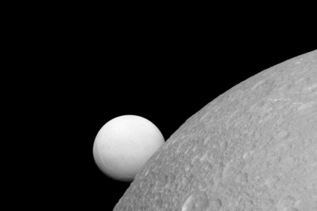Dione con Encelado alle spalle (NASA/JPL–Caltech/Space Science Institute)